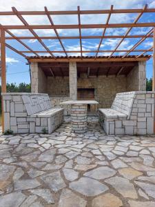a pavilion with a table and two benches on a stone patio at Lio's Villa in Xilokéra