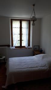 1 dormitorio con cama blanca y ventana en Maison sur Rhue, en Égliseneuve-dʼEntraigues