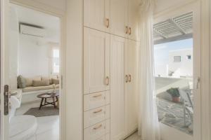 a kitchen with white cabinets and a living room at Piperi-2 Bedroom home in Naousa