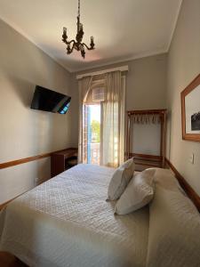 a bedroom with a white bed with a chandelier and a window at Hotel Vicente López in Vicente López