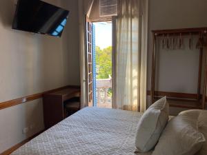 فندق فيسنتي لوبيز في فيسنتي لوبيز: غرفة نوم بسرير وتلفزيون بشاشة مسطحة