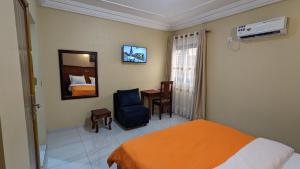 um quarto de hotel com uma cama, uma cadeira e uma secretária em ALICIA HOTEL em Douala