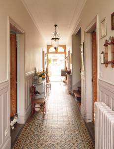 korytarz z podłogą wyłożoną kafelkami i żyrandolem w obiekcie La Cantellerie w mieście Courseulles-sur-Mer