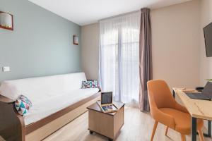 um pequeno quarto com uma cama e uma secretária com um computador portátil em Appart'City Confort Agen Centre em Agen