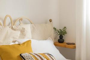 a bed with yellow pillows and a plant on a table at Piperi-2 Bedroom home in Naousa
