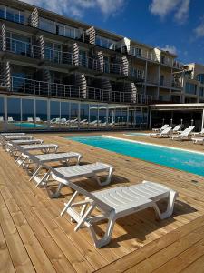 una fila di chaise longue accanto alla piscina di Apart-Hotel Poseidon a Odessa