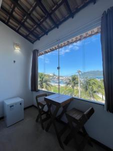 einen Tisch und Stühle in einem Zimmer mit einem großen Fenster in der Unterkunft Hospedagem Pé Na Areia in Arraial do Cabo