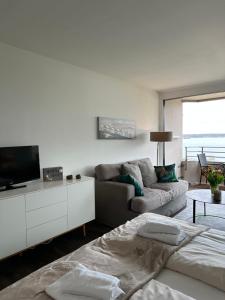 a white living room with a couch and a tv at Weitblick - mit Strandkorb, mehr Meer geht nicht in Glücksburg