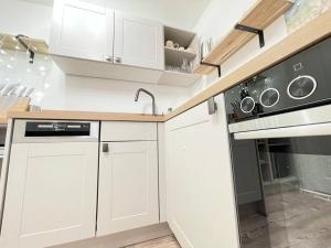 cocina blanca con fregadero y fogones en Gemütliches Appartement 10 Minuten zum Strand, en Graal-Müritz