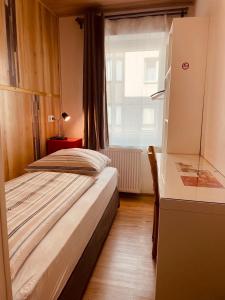 a bedroom with a bed and a desk and a window at Andefu Hotel am Kantpark in Duisburg