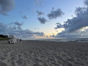 einen Strand mit Stühlen auf dem Sand und dem Meer in der Unterkunft Gemütliches Appartement 10 Minuten zum Strand in Graal-Müritz