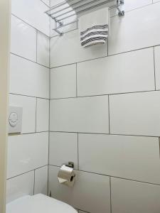 a white tiled bathroom with a toilet and towels at Andefu Hotel am Kantpark in Duisburg