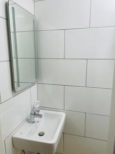 a white bathroom with a sink and a mirror at Andefu Hotel am Kantpark in Duisburg
