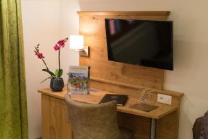 a living room with a tv and a vase of flowers at Hotel Restaurant Hirschen in Interlaken