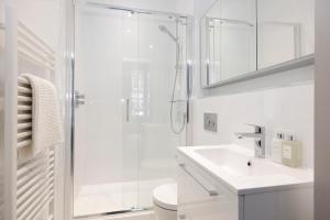 a white bathroom with a shower and a sink at Stylish 3-Bedroom Edinburgh City Getaway in Edinburgh