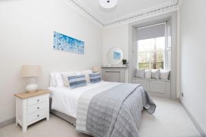 a white bedroom with a bed and a window at Stylish 3-Bedroom Edinburgh City Getaway in Edinburgh