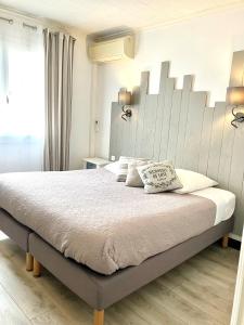 1 dormitorio con 1 cama grande y cabecero grande en Hotel Lou Marquès en Saintes-Maries-de-la-Mer