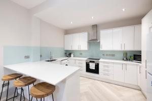 een keuken met witte kasten en een wit aanrecht bij Stylish 3-Bedroom Edinburgh City Getaway in Edinburgh