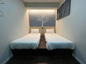 2 camas en una habitación pequeña con un árbol en la pared en OU INN Cameron Highlands ,Ferm Nyonya Restaurant en Tanah Rata