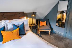 a bedroom with a bed with colorful pillows and a chair at The Ginger Pig in Brighton & Hove