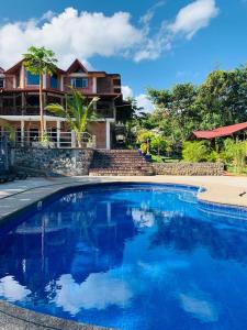 a large blue swimming pool in front of a house at La Casa del Rio B&B in Puyo