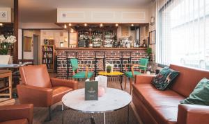 a restaurant with couches and tables and chairs at Hotel Saint Christophe in Le Tilleul