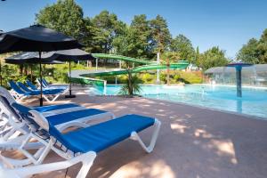 una piscina con dos tumbonas y un tobogán de agua en Camping maeva Escapades Le Domaine Aramis, en Marsan