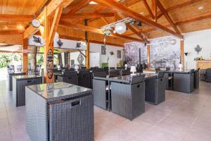 un restaurante con mesas y sillas negras y techos de madera en Camping maeva Escapades Le Domaine Aramis, en Marsan