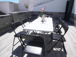 a white table with black chairs and a vase of flowers at Casa Rural Dehesa de Algar in Algar