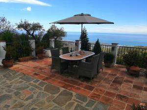 une terrasse avec un parasol, une table et des chaises dans l'établissement La Montaña Del Oro, à Sayalonga
