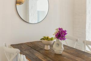 a table with a vase with flowers and a mirror at Piperi-2 Bedroom home in Naousa