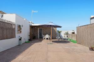 een patio met een tafel en een parasol bij Currimar in Conil de la Frontera