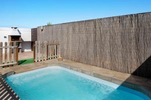 a swimming pool in a backyard with a wooden fence at Currimar in Conil de la Frontera