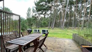 einen Holztisch und Stühle auf einer Terrasse mit Bäumen in der Unterkunft Namelis Preiloje 3 in Preila