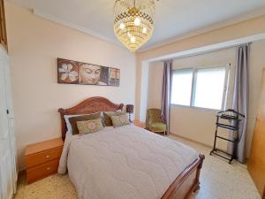 a bedroom with a large bed and a chandelier at 3 bedroom flat with wifi in Valencia