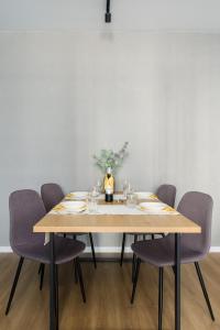 a dining room table with chairs and a bottle of wine at Osiedle Goplana Apartment FREE GARAGE by Renters in Poznań