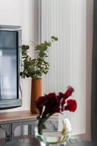 a vase with red flowers in it next to a window at Osiedle Goplana Apartment FREE GARAGE by Renters in Poznań