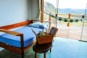 a bedroom with a bed and a basket on a chair at ninho da arara in Sao Jorge