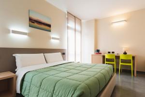 a bedroom with a bed and two yellow chairs at Parini Hotel in Bosisio Parini