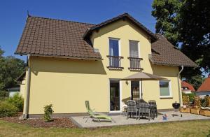 uma casa amarela com cadeiras e um guarda-sol em Ferienwohnungen am Roten Nil em Lübben