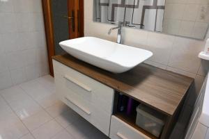 - un lavabo blanc sur un comptoir en bois dans la salle de bains dans l'établissement Hiking Escape Parzanica, à Parzanica