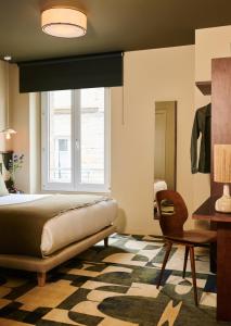 1 dormitorio con cama, ventana y silla en Hôtel Cartier, en Saint-Malo