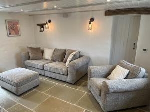 una sala de estar con 2 sofás y una silla en Blacksmiths Cottages en Filey