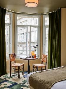 サン・マロにあるホテル カルティエのベッドルーム1室(テーブル、椅子2脚、窓付)