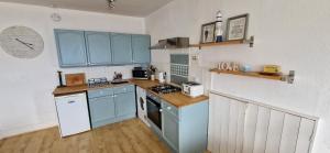 una cucina con armadi blu e piano di lavoro di Entire Apartment, Rothesay, Isle of Bute a Rothesay