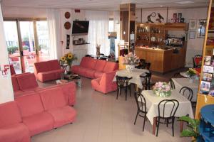 un soggiorno con mobili rossi, tavoli e sedie di Hotel Peonia a Rimini