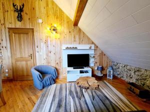 a living room with a tv and a blue chair at Gîte Le Bijou et Spa in Weiterswiller