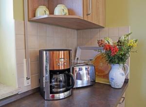 un bancone della cucina con macchinetta del caffè e vaso di fiori di Ferienwohnungen am Roten Nil a Lübben