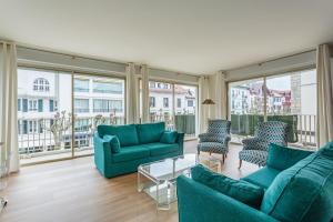 a living room with blue furniture and large windows at Bel appartement en plein centre ville et 50 m de la grande plage in Saint-Jean-de-Luz