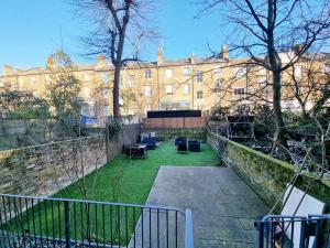 Blick auf ein Gebäude mit einem Garten mit Stühlen in der Unterkunft Oxford Gardens Apartments in London